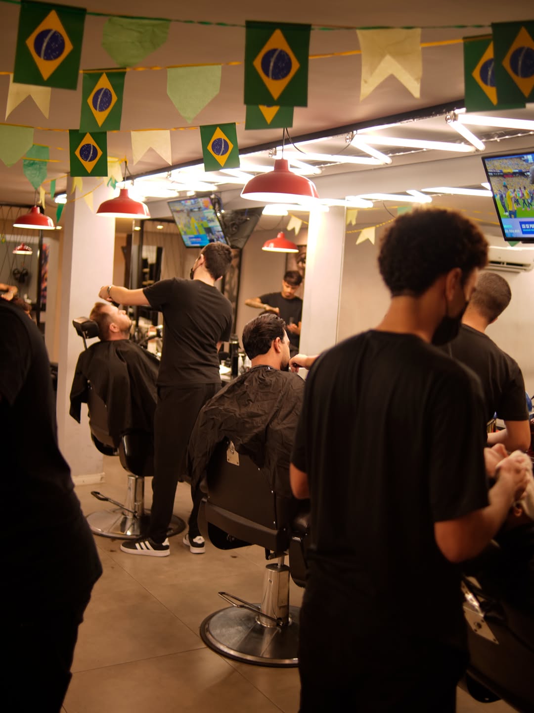 Interior da Barbearia Ricoy com barbeiros atendendo clientes nas cadeiras